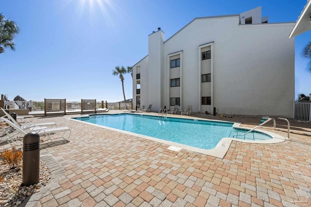 community pool with a patio and fence