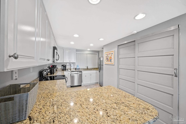 kitchen with recessed lighting, stainless steel appliances, light stone countertops, and white cabinetry