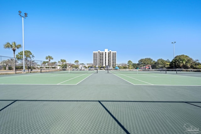 view of tennis court featuring community basketball court and fence