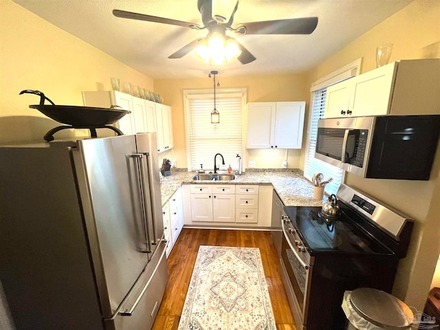 kitchen with pendant lighting, sink, white cabinetry, appliances with stainless steel finishes, and dark hardwood / wood-style flooring