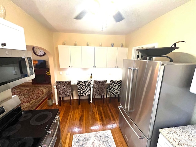 kitchen with stainless steel appliances, light stone countertops, dark hardwood / wood-style floors, and white cabinetry