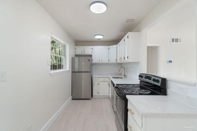 4514 Florelle Way, Pensacola, FL 32505 - kitchen with white cabinets, black range with electric stovetop, tasteful backsplash, a sink, and freestanding refrigerator
