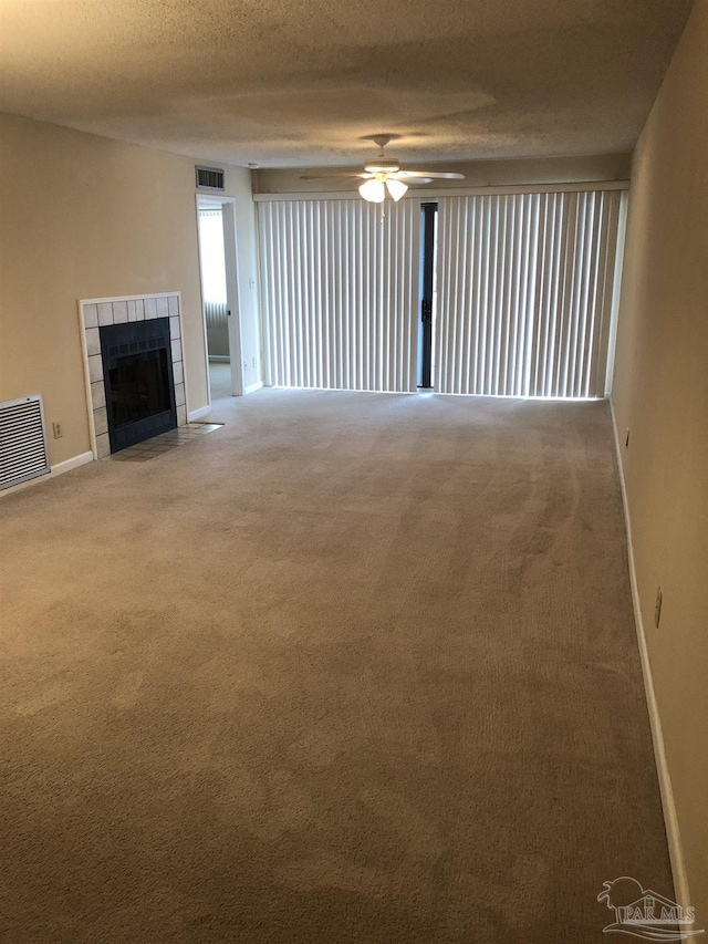 unfurnished living room with ceiling fan, a fireplace, a textured ceiling, and carpet