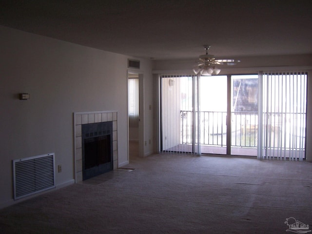 unfurnished living room with ceiling fan, a tiled fireplace, and carpet floors