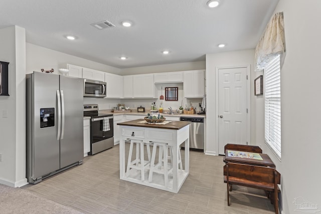 kitchen featuring appliances with stainless steel finishes, visible vents, a sink, and white cabinetry