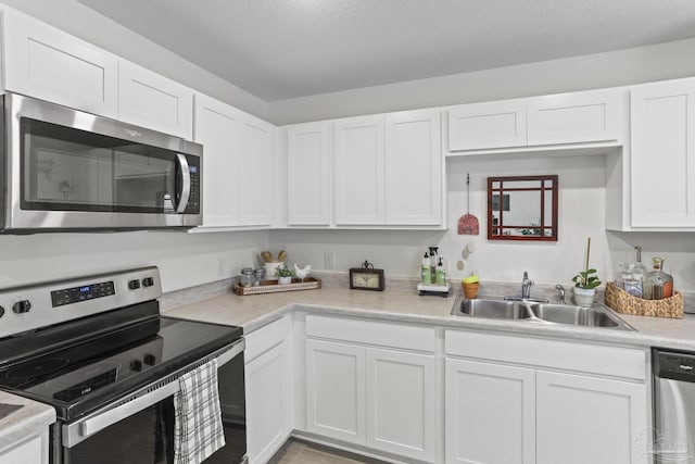 kitchen with white cabinetry, stainless steel appliances, a sink, and light countertops