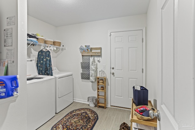 clothes washing area featuring washer and dryer, laundry area, wood finish floors, and baseboards