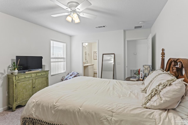 bedroom featuring light carpet, ensuite bath, visible vents, and a ceiling fan