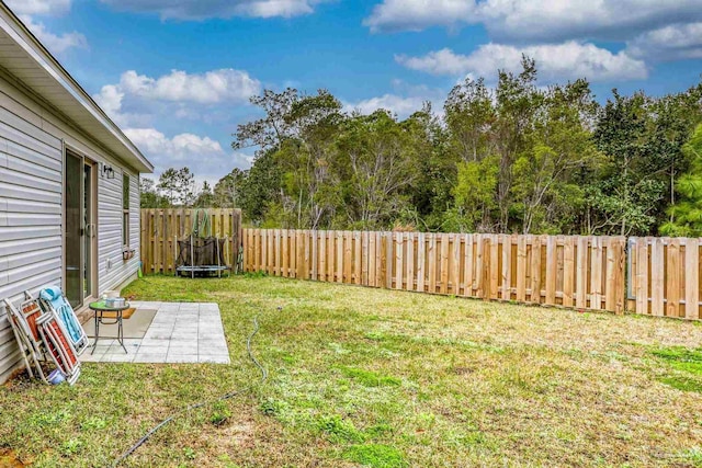 view of yard with a patio area, a fenced backyard, and a trampoline