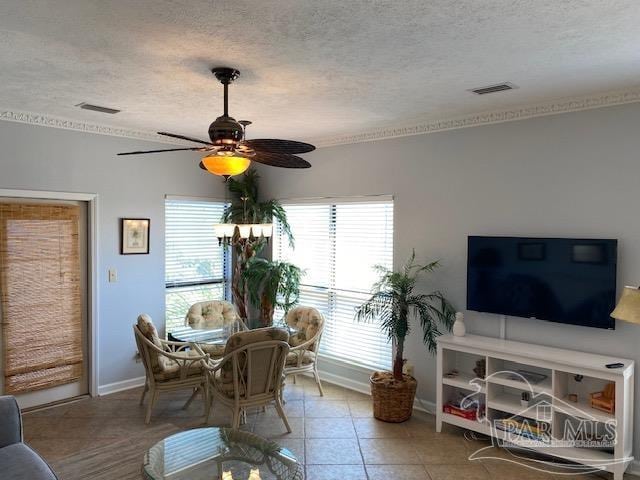 tiled dining room with ornamental molding, ceiling fan, and a textured ceiling