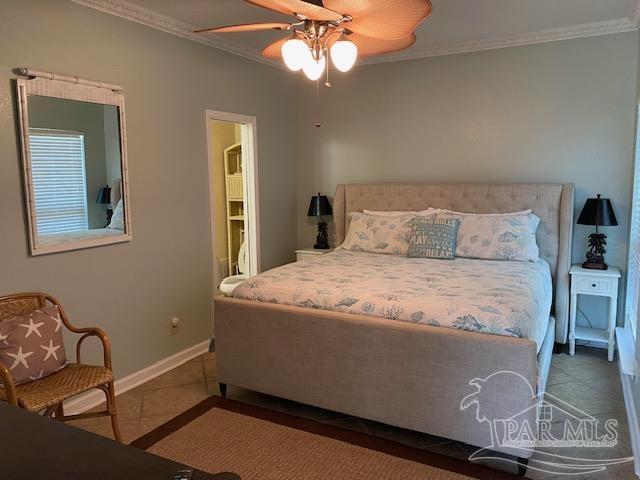 tiled bedroom with ceiling fan, ornamental molding, and connected bathroom