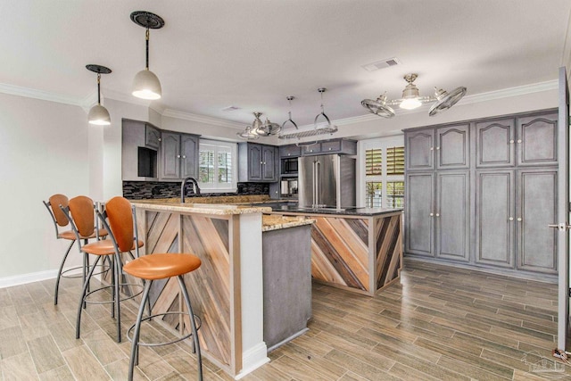 kitchen featuring high end fridge, backsplash, ornamental molding, a kitchen bar, and kitchen peninsula