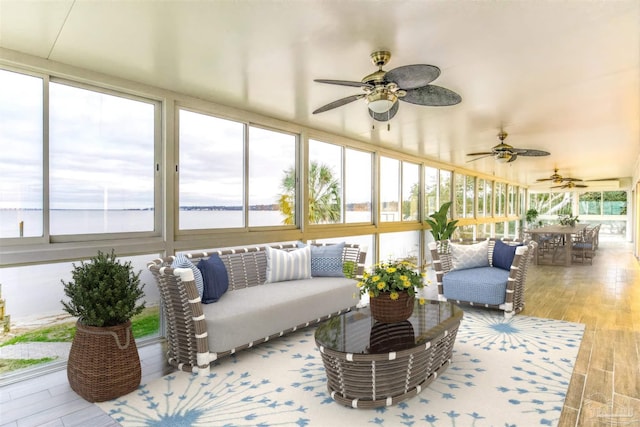 sunroom / solarium featuring a water view and ceiling fan