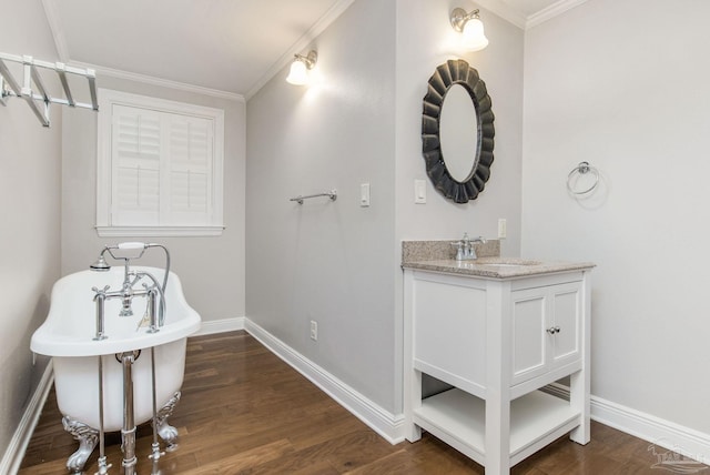 bathroom with ornamental molding, hardwood / wood-style floors, a washtub, and vanity