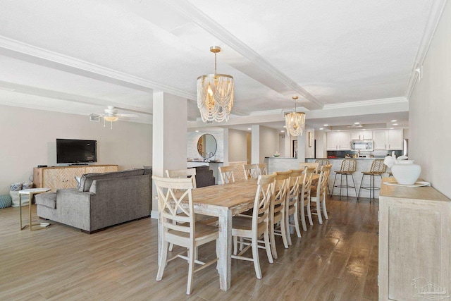 dining space with hardwood / wood-style flooring, ceiling fan with notable chandelier, and crown molding