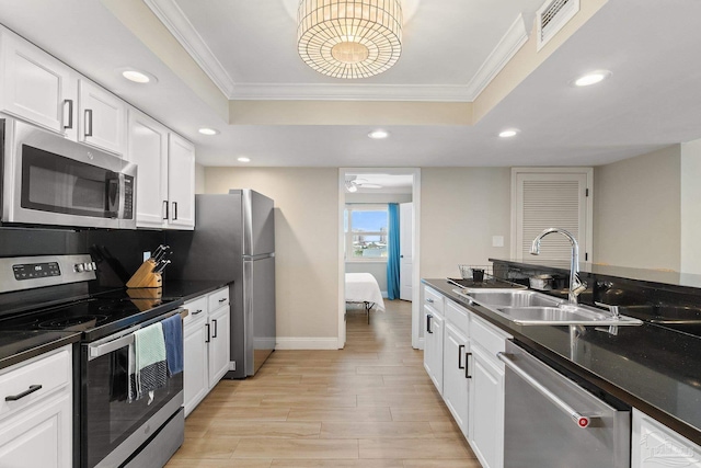 kitchen featuring crown molding, light hardwood / wood-style flooring, stainless steel appliances, a raised ceiling, and sink