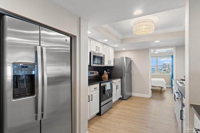 kitchen with white cabinetry, a tray ceiling, light hardwood / wood-style floors, appliances with stainless steel finishes, and decorative backsplash