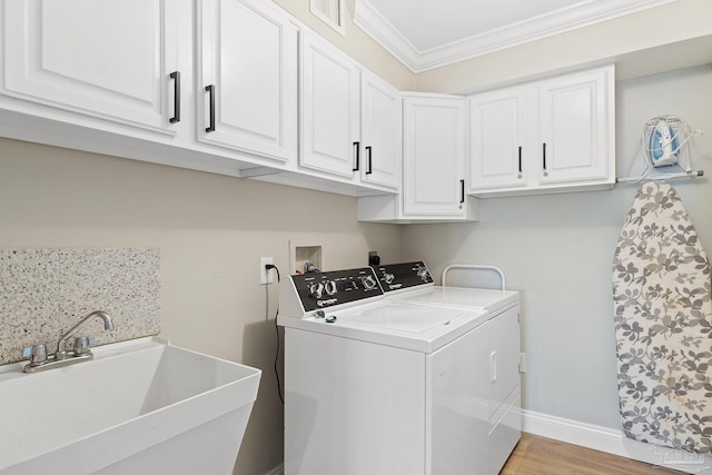 clothes washing area with washer and clothes dryer, ornamental molding, sink, light hardwood / wood-style floors, and cabinets