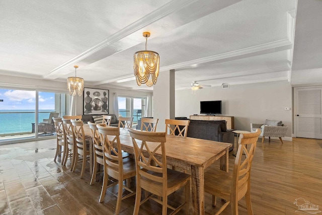 dining space with beam ceiling, a textured ceiling, ceiling fan with notable chandelier, a water view, and hardwood / wood-style floors