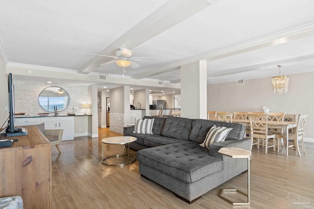 living room featuring beam ceiling, a textured ceiling, ceiling fan with notable chandelier, light hardwood / wood-style floors, and ornamental molding