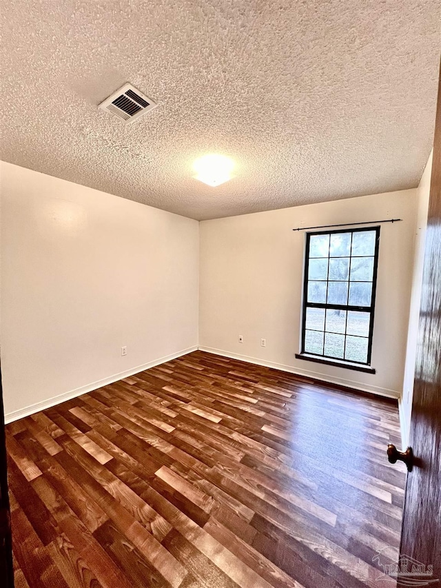 empty room featuring a textured ceiling and dark hardwood / wood-style flooring