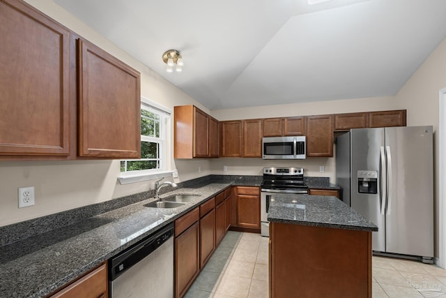 5661 Maggie Rose Cir, Milton, FL 32570 - kitchen featuring appliances with stainless steel finishes, light tile patterned floors, lofted ceiling, dark stone counters, and a kitchen island