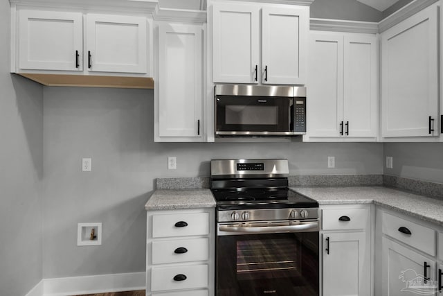 kitchen with appliances with stainless steel finishes, white cabinetry, light countertops, and baseboards