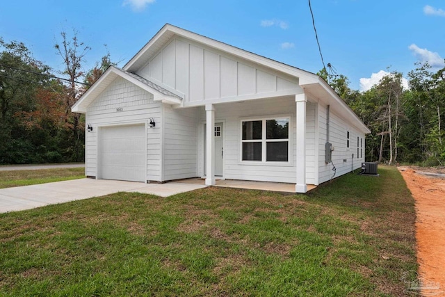view of front of home with board and batten siding, concrete driveway, a front yard, central AC, and a garage