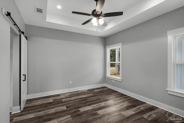 unfurnished bedroom with dark wood finished floors, a tray ceiling, and baseboards