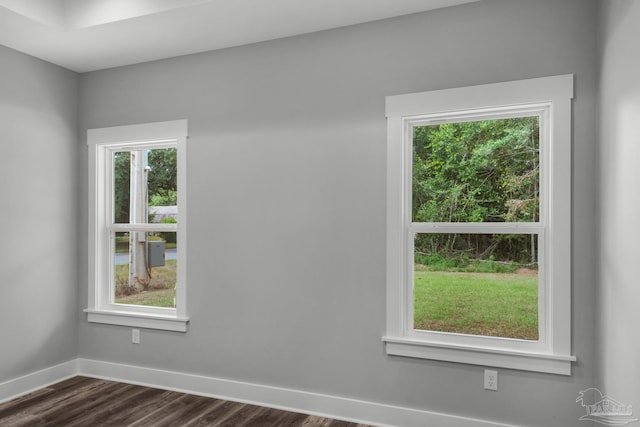 unfurnished room featuring a healthy amount of sunlight, dark wood-type flooring, and baseboards