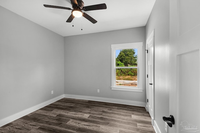 spare room with dark wood-style floors, a ceiling fan, and baseboards