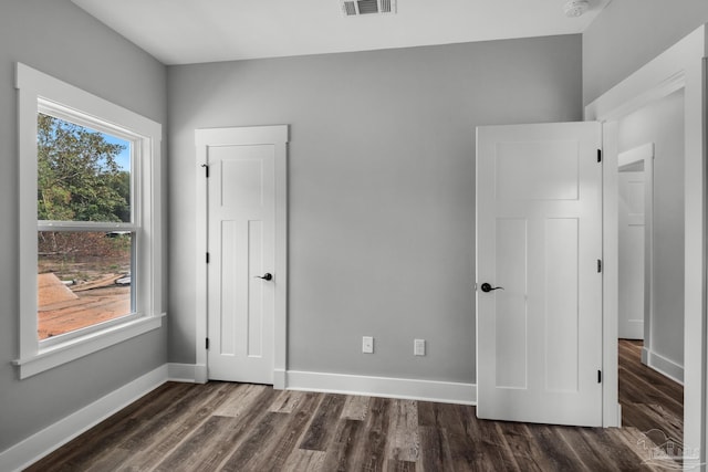 unfurnished bedroom featuring visible vents, dark wood-style floors, and baseboards