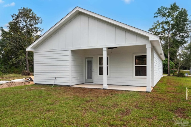 rear view of property featuring a lawn and board and batten siding