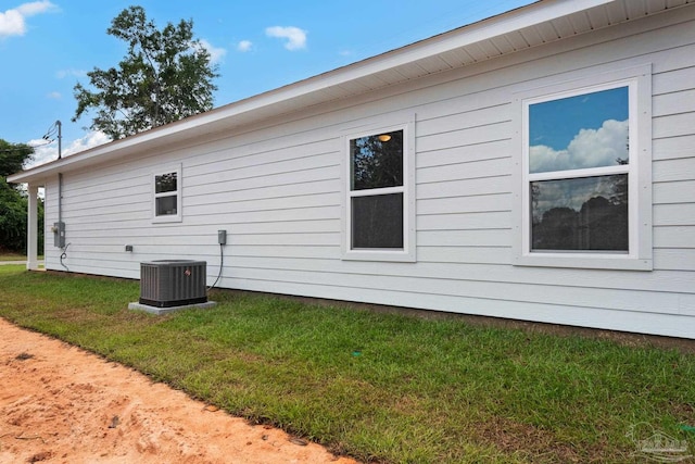 view of home's exterior with a lawn and central AC