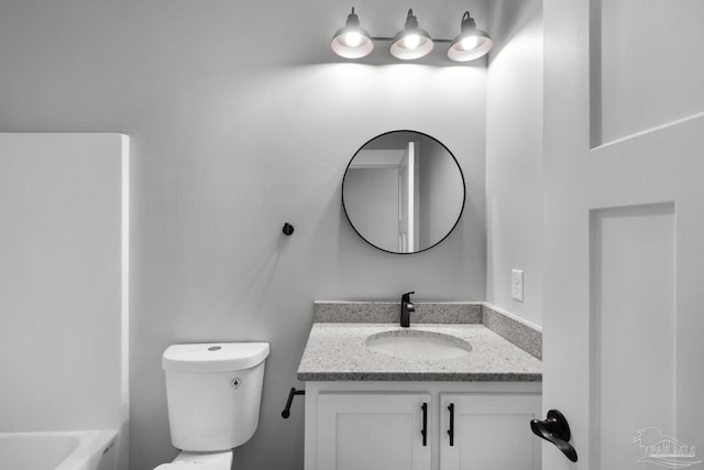 bathroom featuring a tub, toilet, and vanity