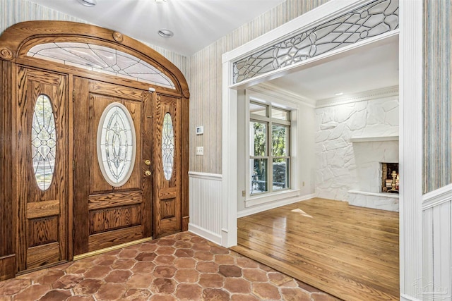 entryway featuring a stone fireplace and ornamental molding