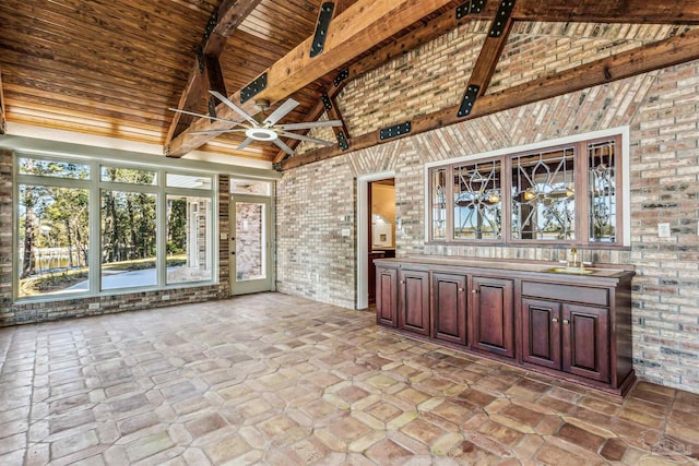 unfurnished sunroom featuring sink, lofted ceiling with beams, wooden ceiling, and ceiling fan