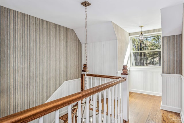 hallway with an inviting chandelier and light wood-type flooring