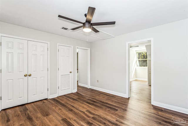 unfurnished bedroom with multiple closets, dark hardwood / wood-style flooring, and ceiling fan