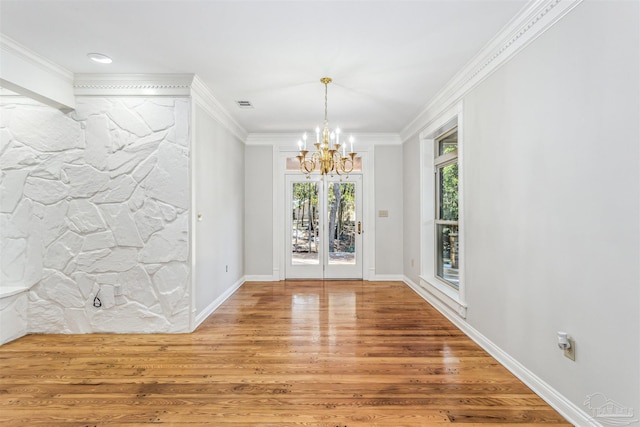 unfurnished dining area with hardwood / wood-style flooring, ornamental molding, and an inviting chandelier