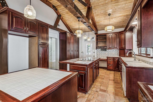 kitchen with sink, tile countertops, hanging light fixtures, a kitchen island with sink, and decorative backsplash