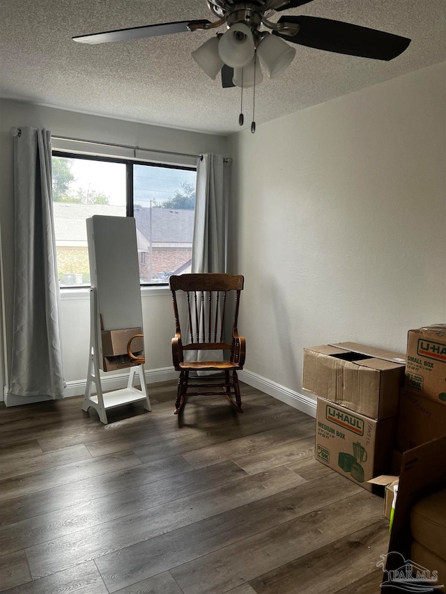 living area featuring ceiling fan, dark hardwood / wood-style flooring, and a textured ceiling