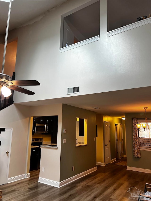 unfurnished living room with ceiling fan with notable chandelier and dark hardwood / wood-style flooring