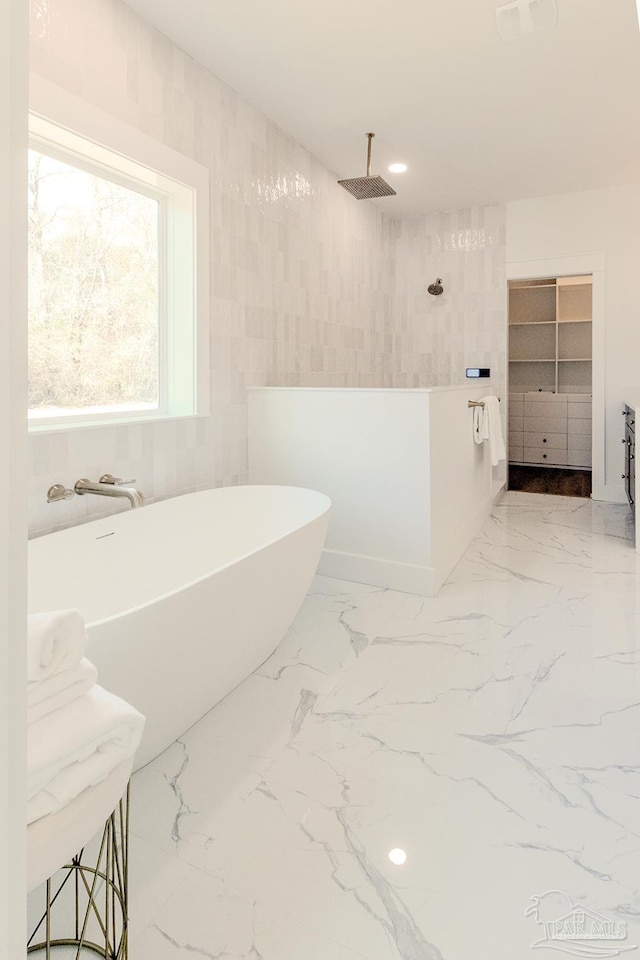 bathroom featuring shower with separate bathtub and tile walls