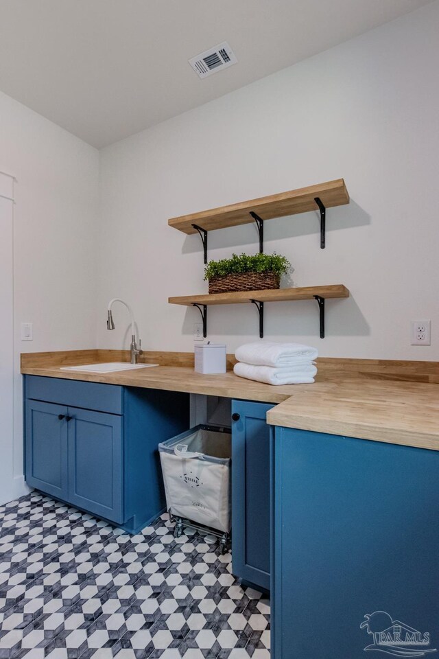 interior space featuring blue cabinets, butcher block counters, and sink