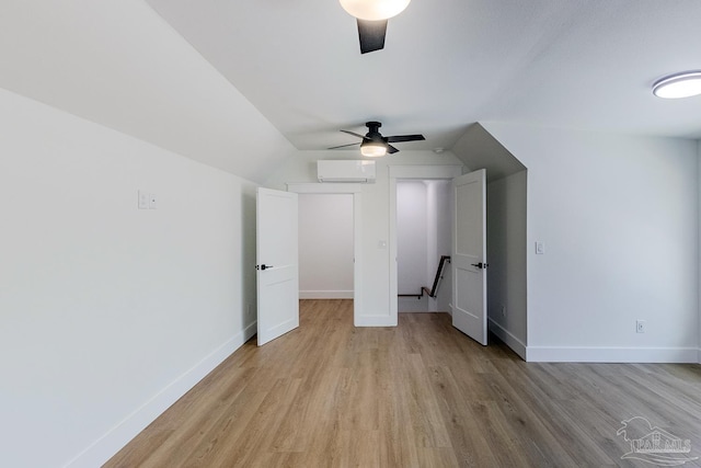 interior space with vaulted ceiling, a wall mounted AC, ceiling fan, and light hardwood / wood-style flooring