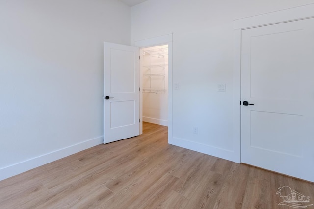 unfurnished bedroom featuring a walk in closet, light hardwood / wood-style floors, and a closet