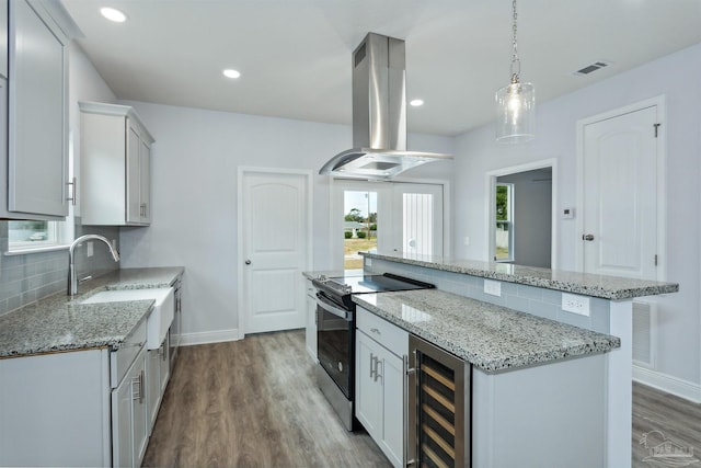 kitchen featuring a center island, beverage cooler, decorative backsplash, range with electric stovetop, and island range hood