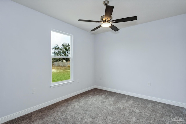 empty room featuring baseboards, dark colored carpet, and ceiling fan