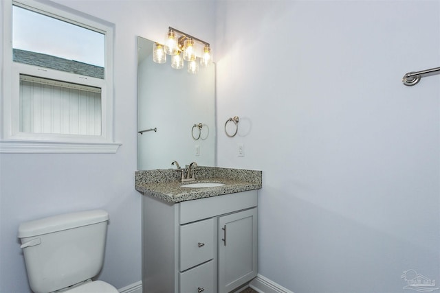 half bath featuring baseboards, toilet, and vanity